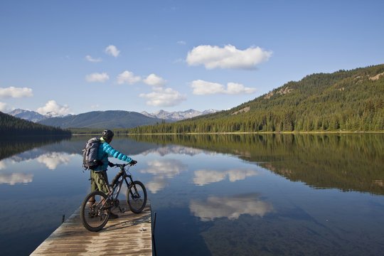 A male mountain biker enjoys a peaceful  moment in the morning before an all day ride in Spruce Lake Protected Area, Southern Chilcotins, British Columbia, Canada