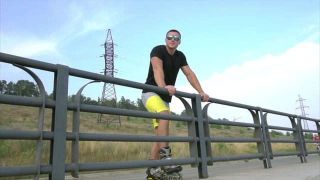 Young sporty man in sunglasses have a brack after roller skating on the seafront HD