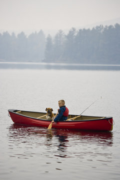 Young boy going fishing with dog in canoe on Source Lake, Algonquin Provincial Park, Ontario, Canada.