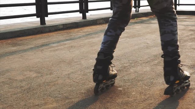 Mans legs roller skating inline close up on the asphalt sunset HD