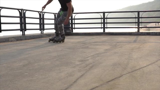 Mans legs roller skating inline close up on the asphalt sunset HD
