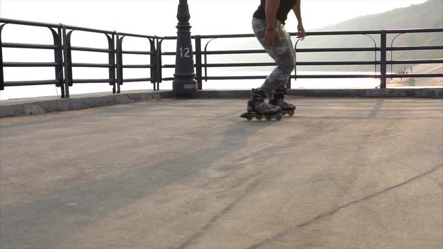 Mans legs roller skating inline close up on the asphalt sunset HD