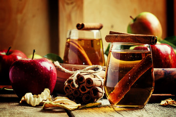 Apple juice with cinnamon in a glass and fresh apples on a vinta
