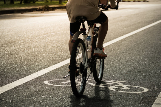 old man riding bicycleon bike lane in evening sunlight