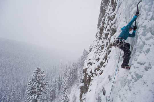A strong female climber ice climbs Moonlight WI4, Even Thomas Creek, Kananaskis, Alberta, Canada