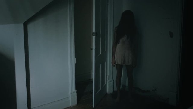 Creepy possessed girl twitching behind a door