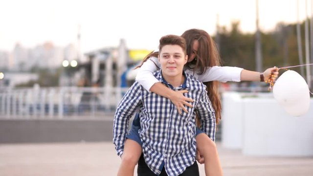 Cheerful girl jumping on boyfriend's back and kissing him, couple having fun