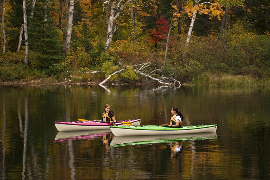 Two young women kayaking on Oxtongue Lake in autumn, Mukoka, Ontario, Canada.