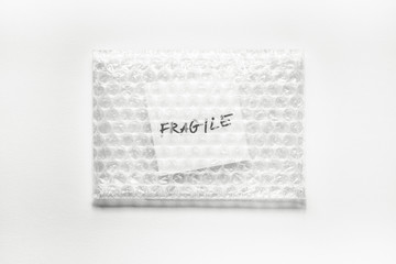 fragile, handwriting on white squre paper in bubble pack, white paper background