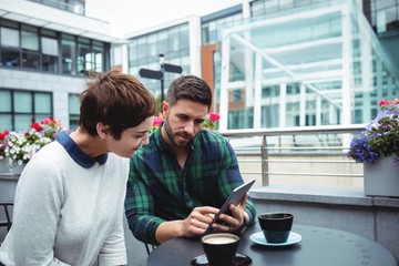 Businesspeople discussion on digital tablet while having coffee
