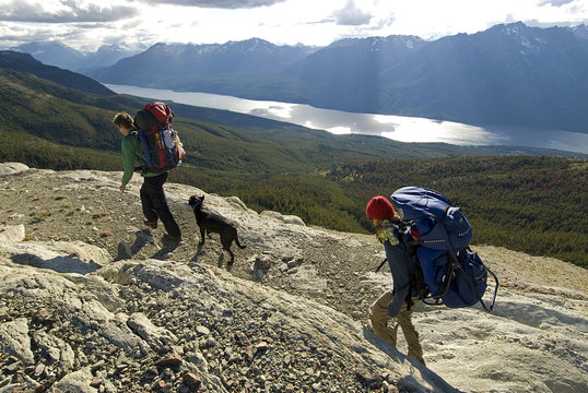 A young couple with their dog and baby hiking on a ridge in the Potato Range with Tatlayoko Lake below, Chilcotins, British Columbia, Canada