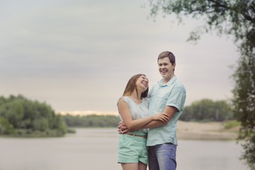 Lovers man and woman standing on the river Bank laugh and have fun, turquoise clothes.