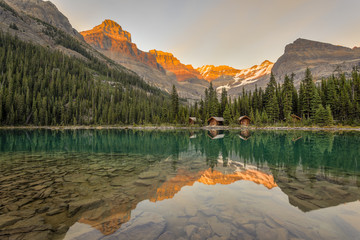 Lake O'Hara Lodge guest cabins and peaks are reflected in the calm lake at sunset. Lake O'Hara, Yoho National Park, British Columbia Canada.No Property Release