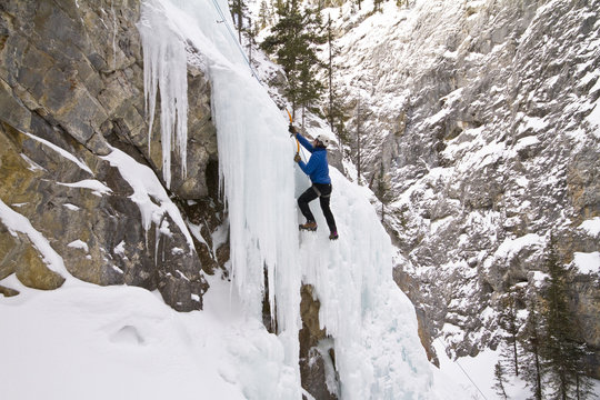 Young man ice-climbing in Banff National Park near Banff, Alberta, Canada.