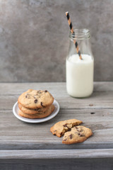 Classic combination: milk and chocolate chip cookies on a rustic weathered wood table 