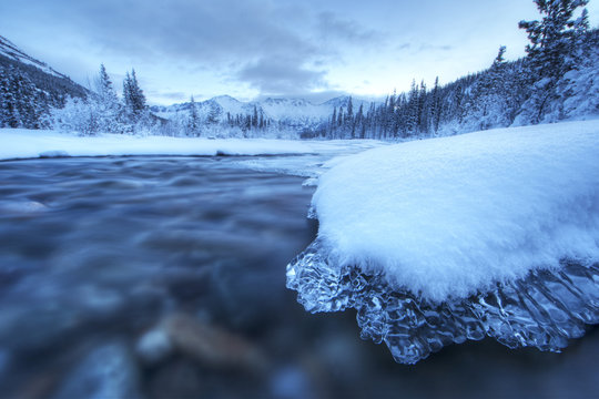 Dawn over a an ice covered rock situated in the Wheaton River which is near Whitehorse, Yukon. 