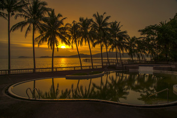 sunset on the paradise beach with coconut tree and reflection on the swimming pool
