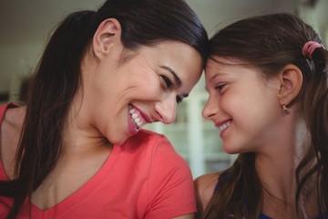 Mother and daughter looking face to face and smiling