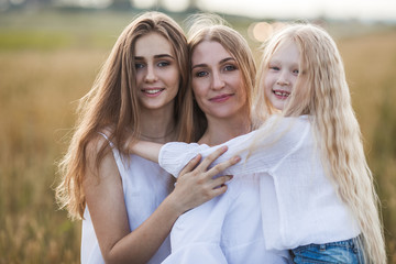 beautiful young mother and her daughters at the wheat field