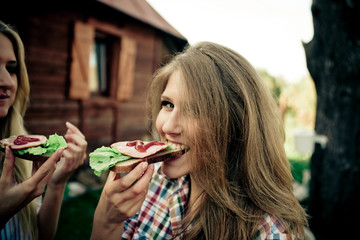 Pretty girl in plaid shirt bites a sandwich