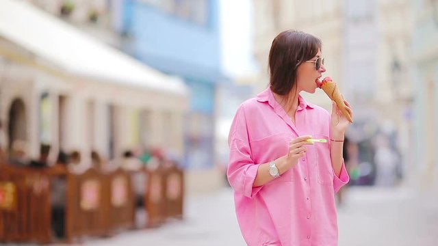 Young female model eating ice cream cone outdoors. Summer concept - woamn with sweet ice-cream at hot day