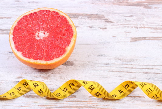 Fresh ripe grapefruit and centimeter on old wooden background