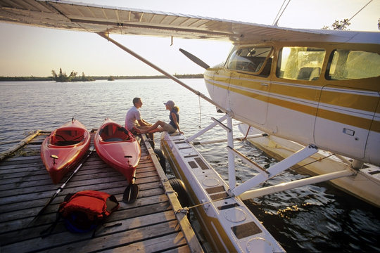 Couple with kayaks on dock, Otter Falls, Whiteshell Provincial Park, Manitoba, Canada.