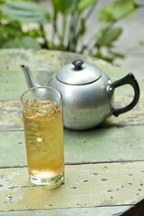 Glass of cold green tea with ice cubes and kettle