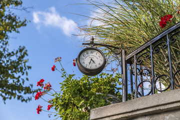 Naklejka premium Street clock on the fence in the countryside a summer day