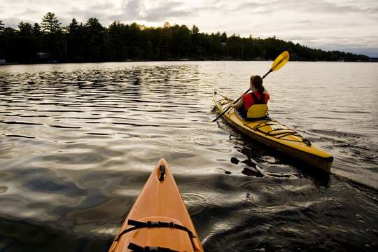 Young woman sea kayaking through Gull Narrows near Gravenhurst, Muskoka, Ontario, Canada.