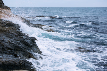 Deep dark blue sea waves breaking on a rocks forming a sea foam.