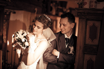 Groom stans behind a bride while she adjusts flowers in her wedd