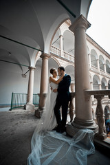 Bride's long veil lies on the floor while she hugs groom on the