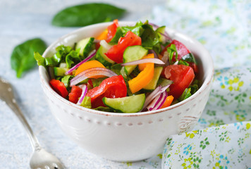 Vegetable salad with spinach, tomato and cucumber on a concrete