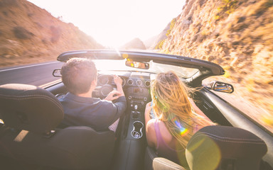 Couple driving fast on a sport convertible car in the canyons. 