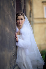 Gorgeous bride with deep eyes leans to the stone wall