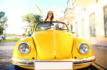 Happy to travel together. Joyful young couple smiling while riding in onvertible