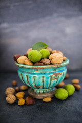Nuts in old vase on a stone dark background. Beautiful autumn still life with copy space.