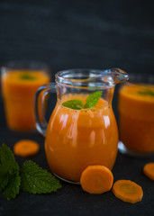 Fresh carrots and carrot juice on dark stone background. Healthy diet and detox.