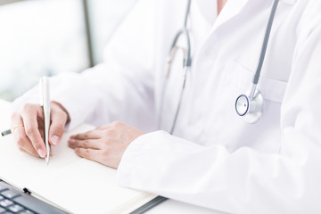 Close-up view of female doctor hands filling patient registratio