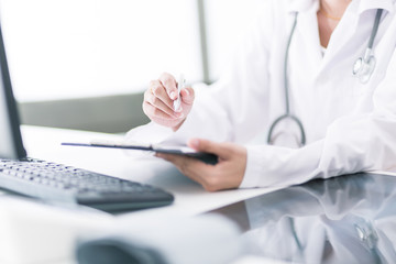 Close-up view of female doctor hands filling patient registratio