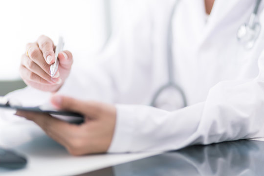 Close-up view of female doctor hands filling patient registratio