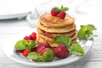 Tasty pancakes with berries and mint on plate