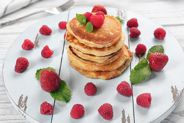Tasty pancakes with berries and mint on wooden board