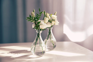 Beautiful flowers in glass vases on wooden table indoors