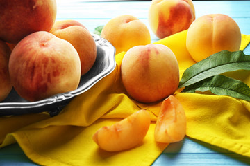 Fresh juicy peaches on yellow napkin and turquoise wooden background