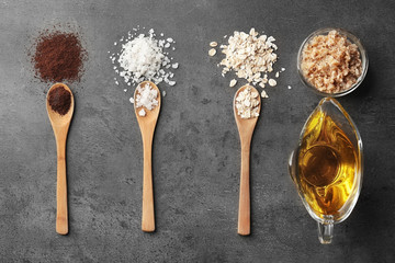 Wooden spoons with natural ingredients for homemade scrub on grey background