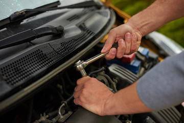 Mechanic use wrench to repair yellow car.