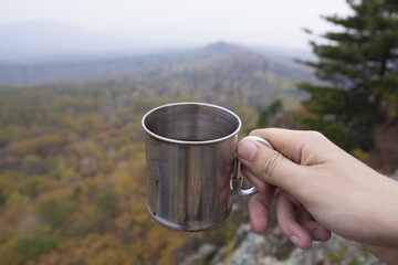Obraz premium Hand holding a mug hiking in the mountains (first person view)