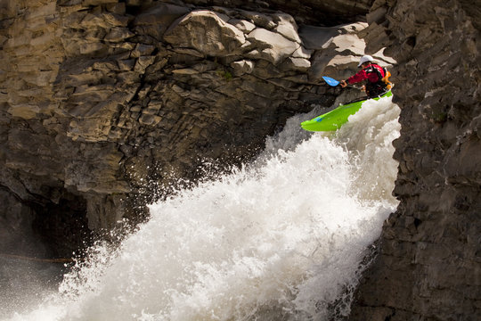 A male whitewater kayaker blasts through a waterfall on the Big Horn River, Nordegg, Alberta, Canada